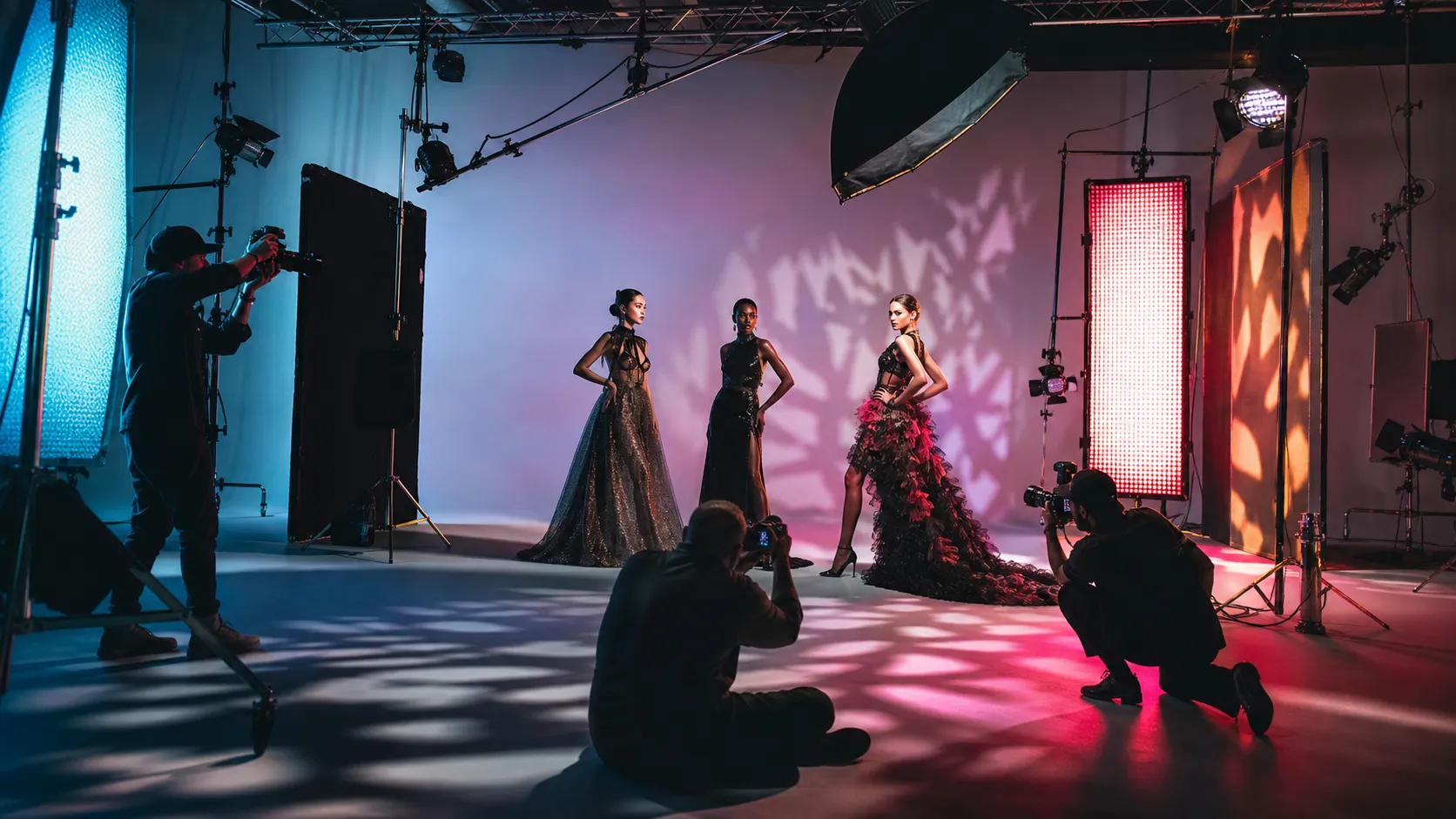 A fully produced studio fashion shoot — three models under dramatic gelled lighting